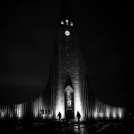 Scène nocturne en noir et blanc à Reykjavik avec silhouettes.