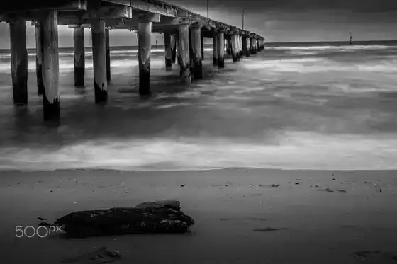 Pose longue en noir et blanc d’une jetée, mer minimaliste.